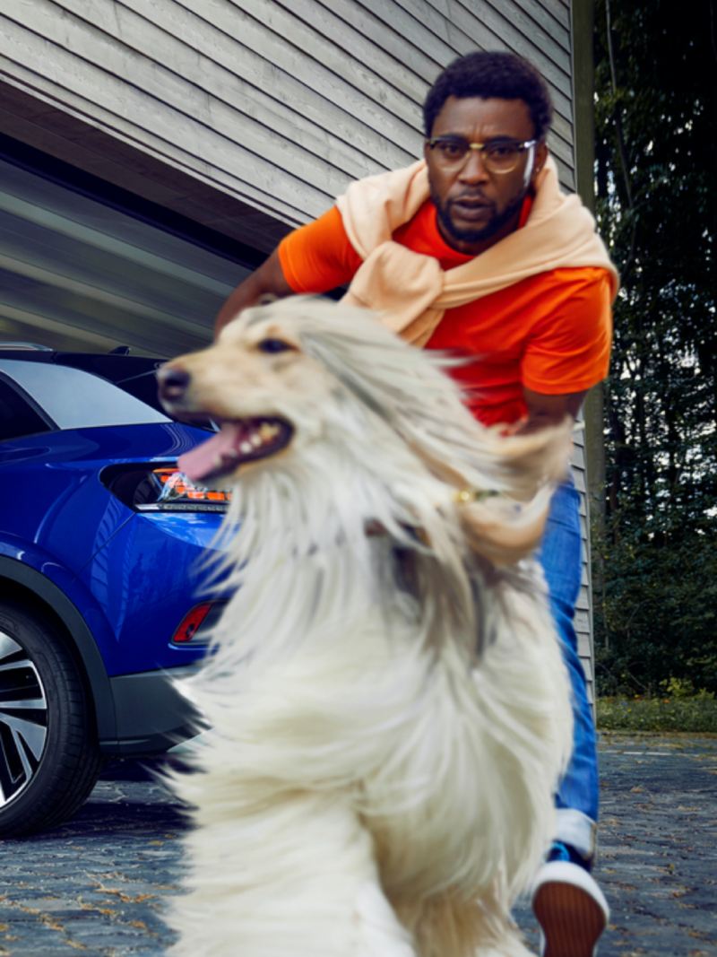 Hombre con un perro delante de un Volkswagen ID.4 azul