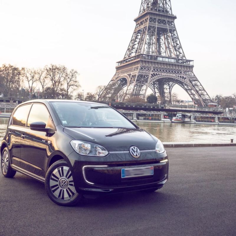 Volkswagen e-up! negro aparcado junto al río Sena con la Torre Eiffel de fondo