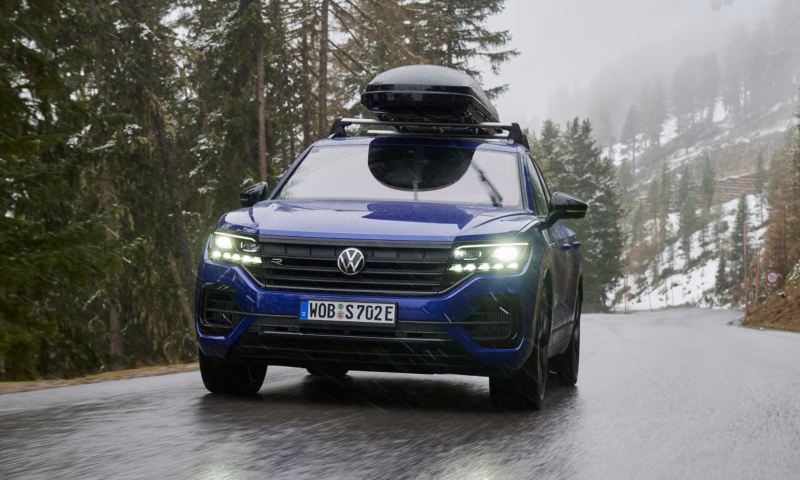 Parte delantera de un Volkswagen Touareg R azul circulando por una carretera nevada.