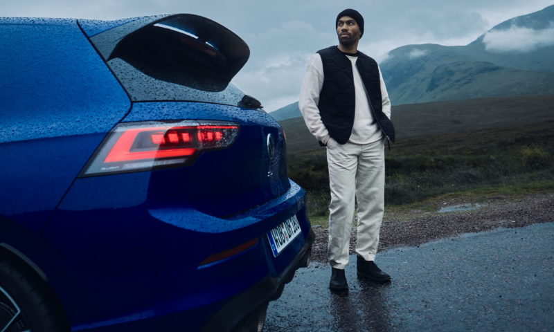 Chico al lado de un Volkswagen T-Roc R azul estacionado