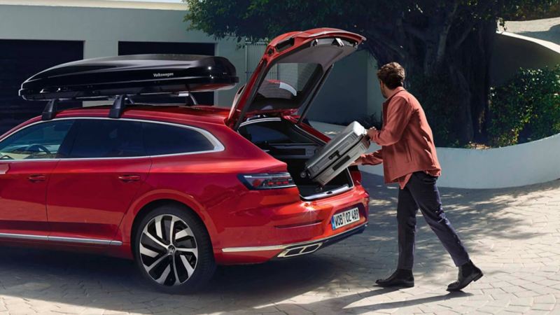 Un hombre cargado el maletero de un Volkswagen Arteon Shooting Brake rojo
