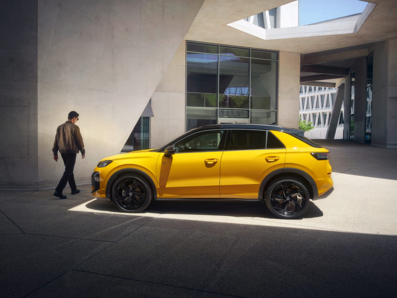 Un hombre al lado de un Volkswagen Nuevo T-Roc de color amarillo estacionado en la calle