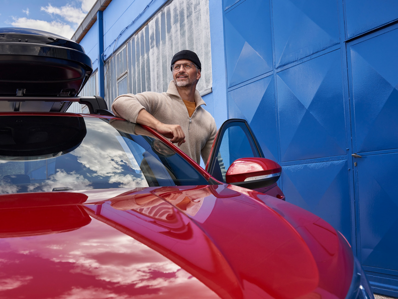 Un hombre entrando en el interior de un Volkswagen Taigo de color rojo estacionado en la calle