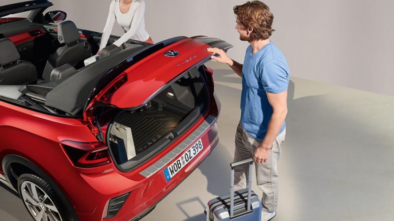 Una pareja cargando el maletero de un Volkswagen T-Roc Cabrio rojo