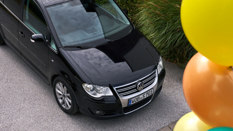 Vista desde arriba de la parte delantera de un Volkswagen Touran negro y unos globos