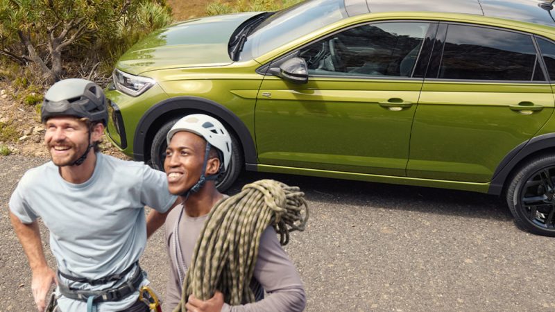 Dos chicos delante de un Volkswagen Taigo de color verde estacionado en la calle