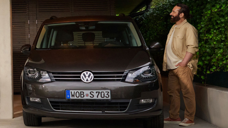 Un chico junto la puerta del conductor de un Volkswagen Touran negro