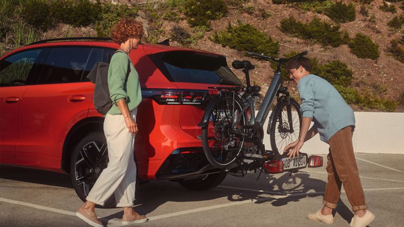 Una pareja poniendo una bicicleta en un Volkswagen de color rojo