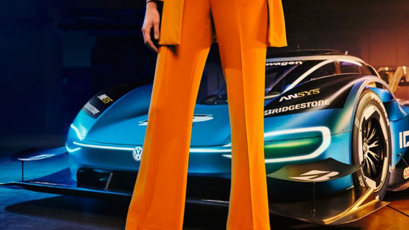 Volkswagen ID. R visto de frente con una chica vestida de naranja vista parcialmente