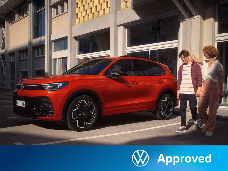 Una madre y su hijo junto a un Volkswagen Tiguan de color rojo estacionado en la calle
