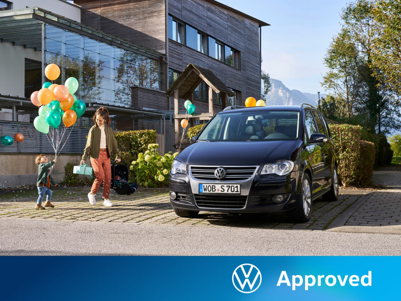 Una madre y su hijo sujetando unos globos junto a un Volkswagen Touran