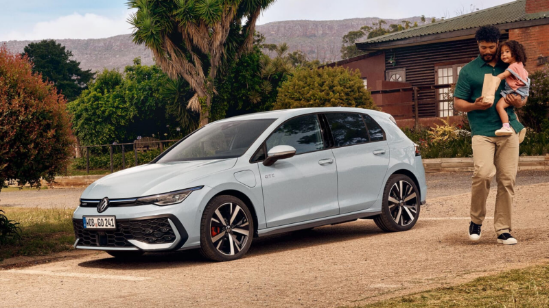 Un padre y una hija junto a un Volkswagen Golf GTE de color gris estacionado fuera de una casa