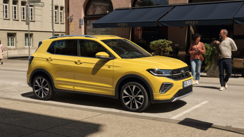 Un Volkswagen T-Cross de color amarillo estacionado en la calle al lado de un establecimiento