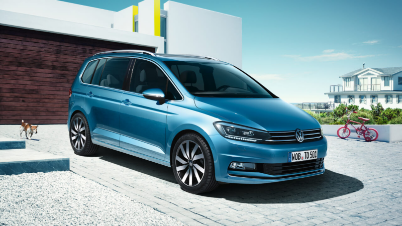 Un Volkswagen Touran de color azul estacionado fuera de una casa