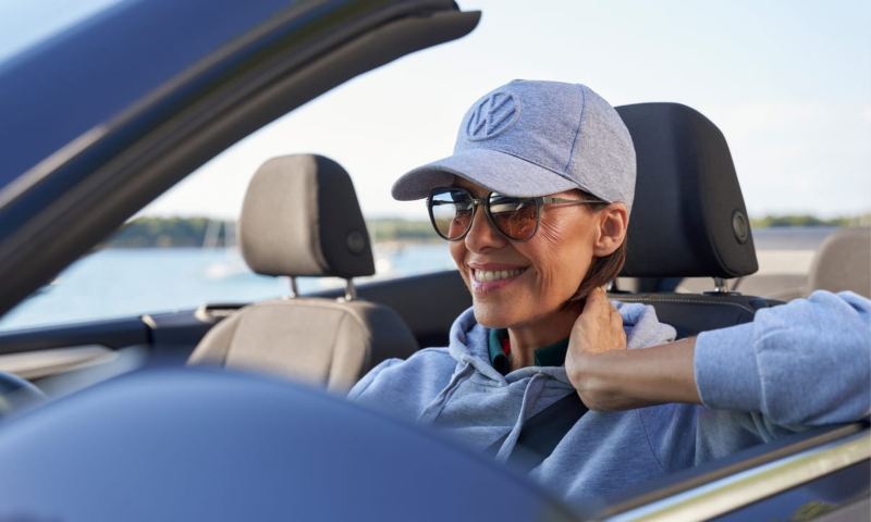 Una chica con una gorra de Volkswagen conduciendo un T-Roc Cabrio