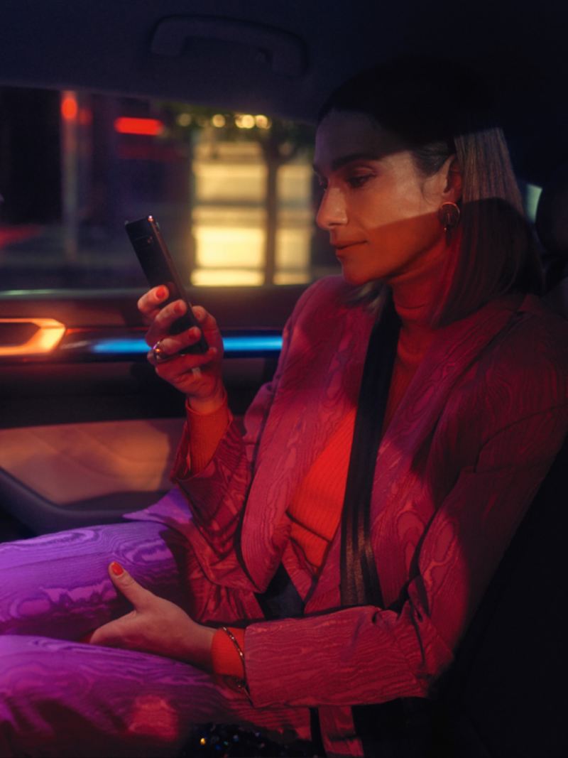 Mujer mirando su móvil sentada en el asiento del acompañante de un Nuevo Volkswagen Arteon