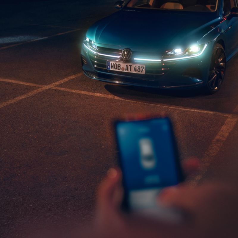 Vista subjetiva de la aplicación We Connect junto a un Nuevo Volkswagen Arteon azul