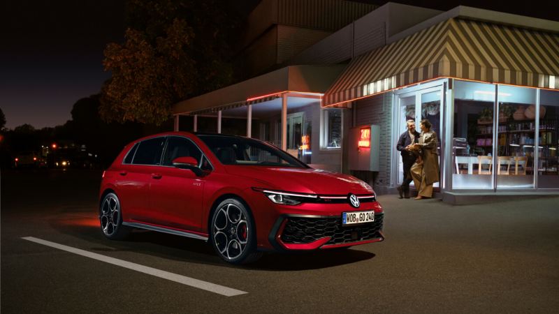 Un Volkswagen GTI de color rojo estacionado fuera de un establecimiento por la noche