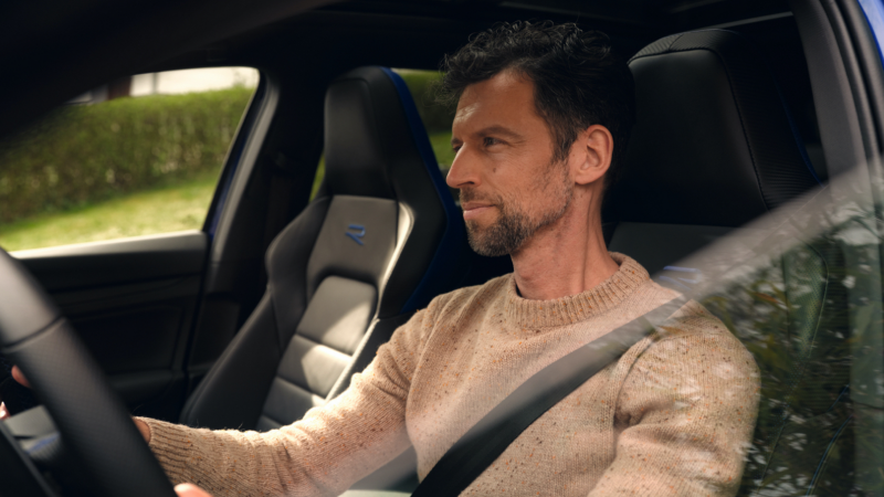 Primer plano de un hombre al volante de un Volkswagen Golf 8 Variant R visto a través de la ventanilla