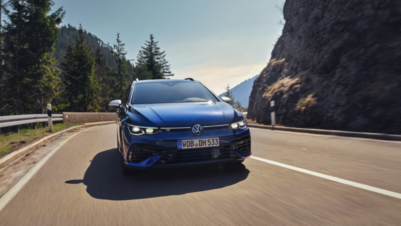 Volkswagen Golf 8 Variant R azul visto de frente en una carretera con árboles y montañas detrás