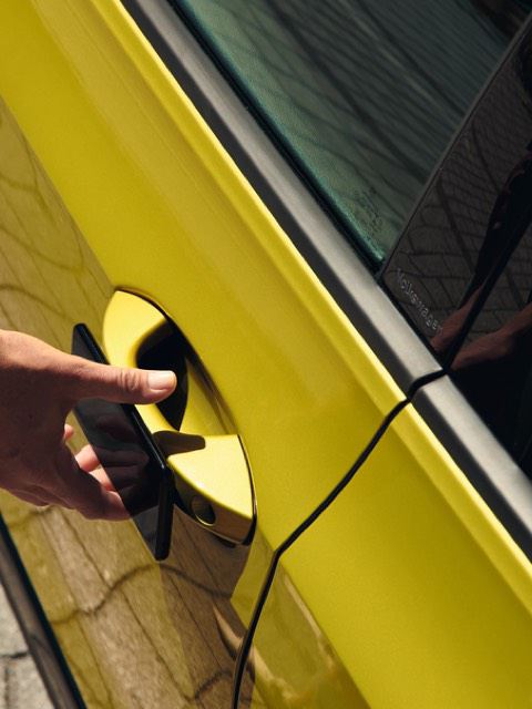 Detalle de una mano abriendo la puerta de un Volkswagen Golf 8 Variant amarillo