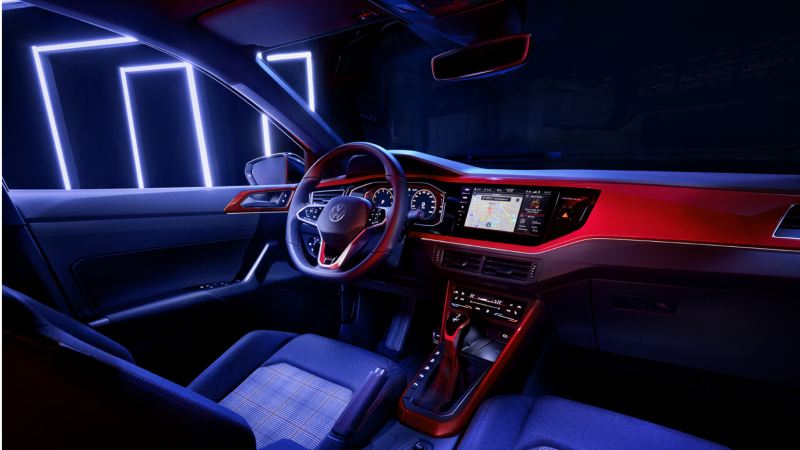 ALT: Volkswagen Polo GTI vista del panel interior. El coche se encuentra dentro de una nave iluminada por luces de neon.