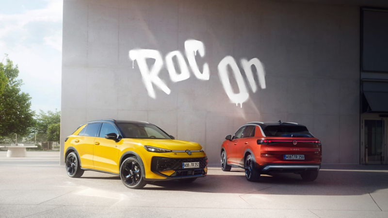 Un Nuevo Volkswaqgen T-Roc rojo y otro amarillo delante de un muro con un grafiti que dice "Roc on"