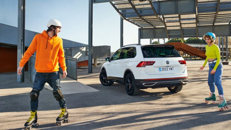 Pareja patinando delante de un Volkswagen Urban Sport blanco
