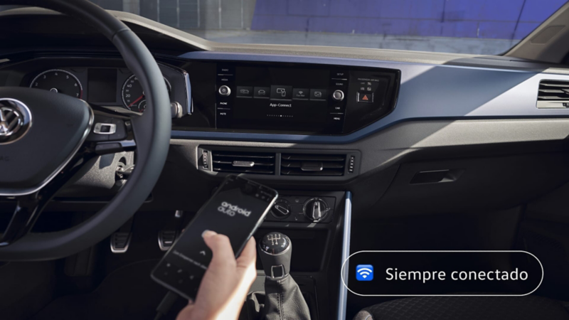 Detalle de una mano con un móvil y el salpicadero de un Tiguan 20 aniversario