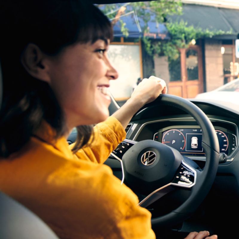 Primer plano de una chica conduciendo un Volkswagen Tiguan y el volante multifunción