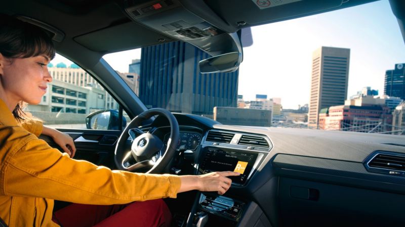 Chica dentro de un Volkswagen Tiguan usando la pantalla interactiva del salpicadero