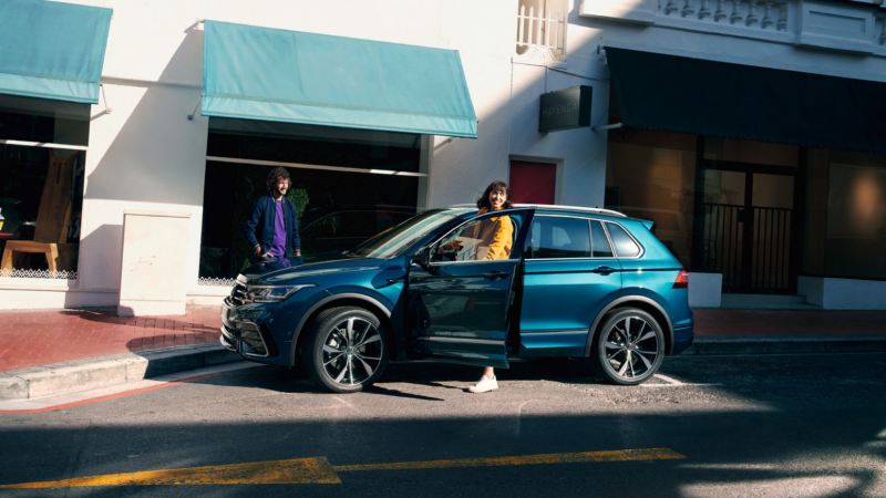 Chica subiendo a un Volkswagen Tiguan azul aparcado en la calle