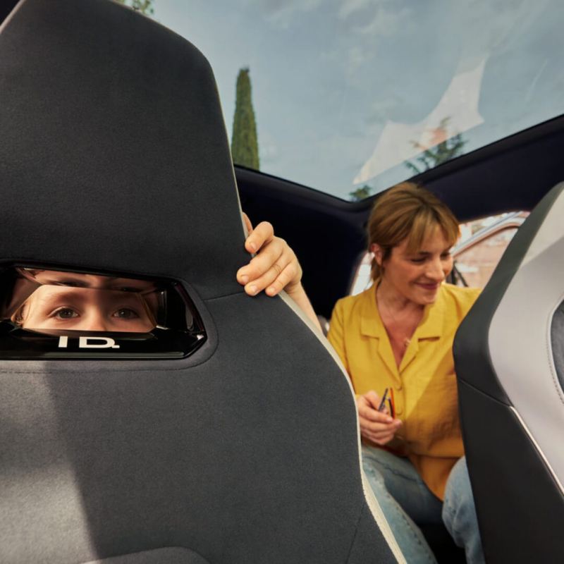 Madre e hijo sentados en la parte trasera de un Volkswagen ID.3 vistos a través de los asientos delanteros
