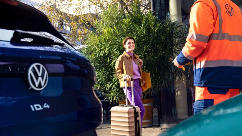 Mujer con una maleta y un agente de servicio de Volkswagen de espalda con una llave