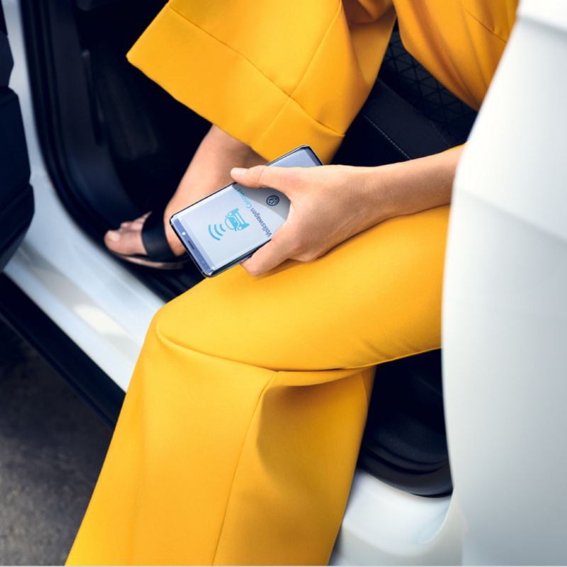 Detalle de un móvil en la mano de una chica vestida de amarillo