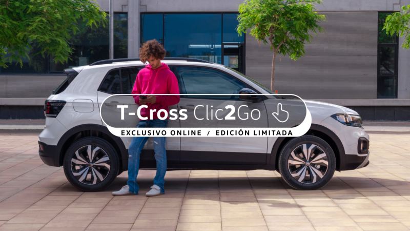 Volkswagen T-Cross gris visto de costado delante de un muro gris y un chico de pie al costado