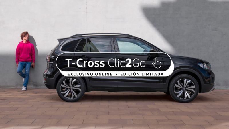 Volkswagen T-Cross gris visto de costado delante de un muro gris y un chico de pie al costado