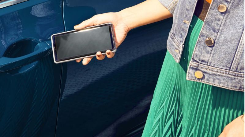 Mujer acercando un móvil a la cerradura de un Volkswagen Passat Variant GTE