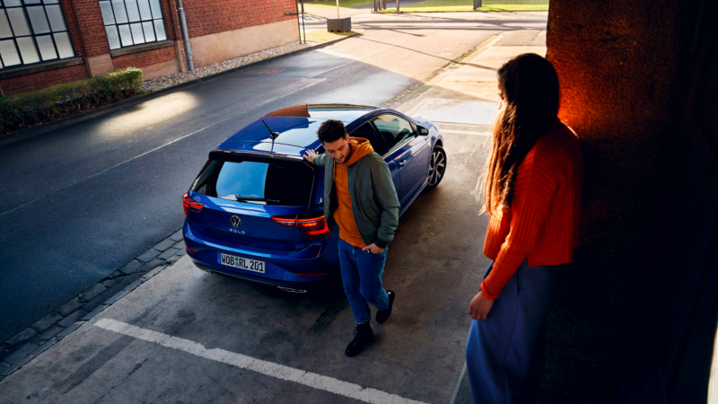 Una chica mirando un Volkswagen Polo de color azul