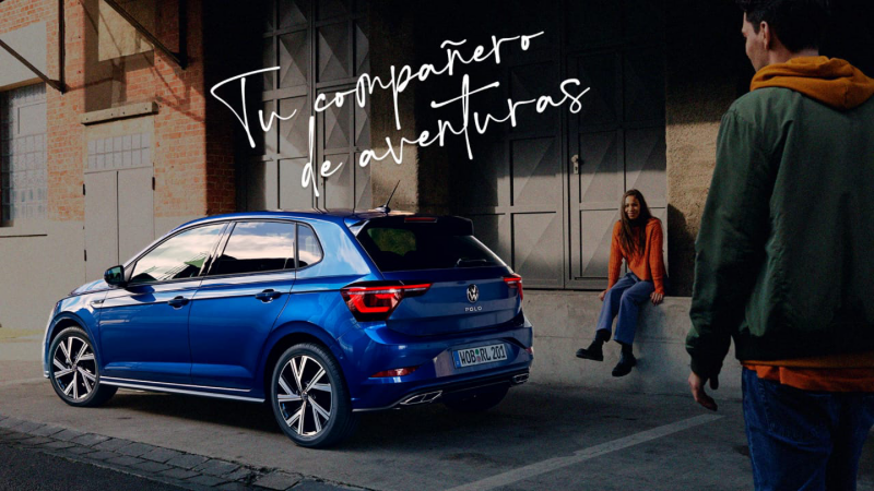 Una chica junto a un Volkswagen Polo de color azul estacionado en la calle