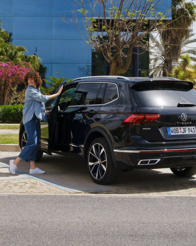 Mujer abriendo la puerta de un Volkswagen Tiguan negro de sustitución