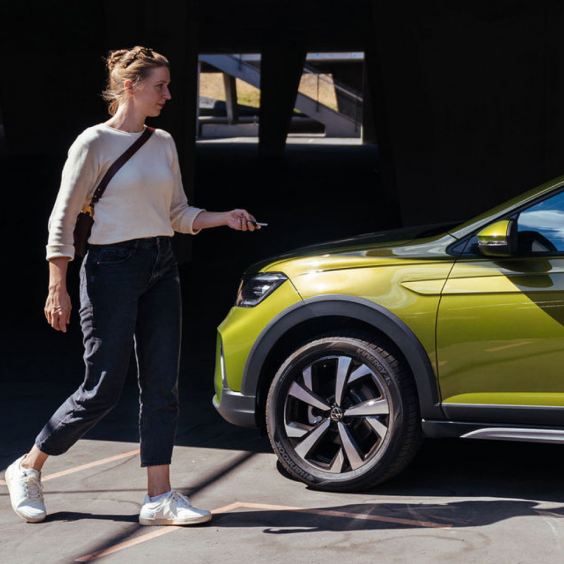 Mujer al lado de un Volkswagen de color verde