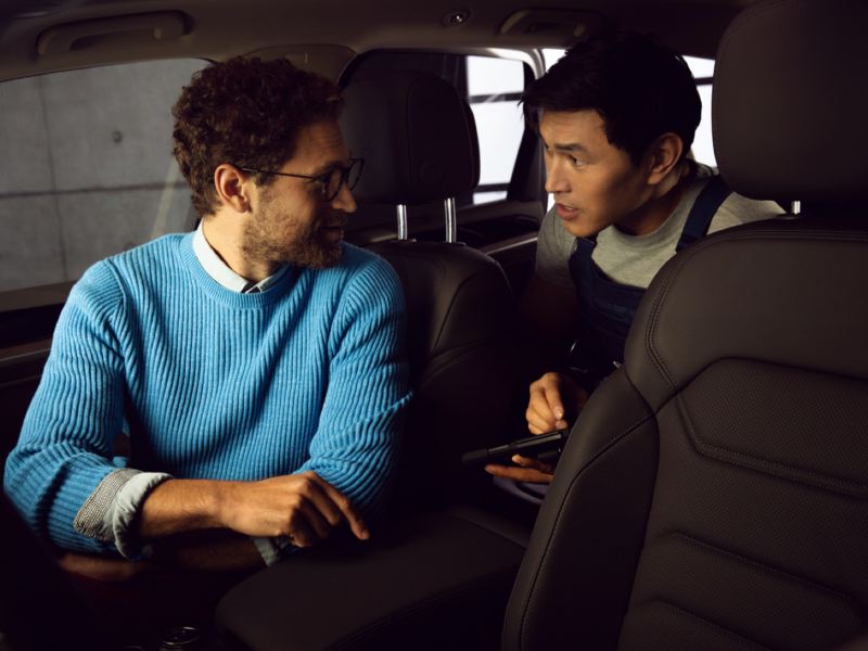 Un empleado de servicio de Volkswagen hablando con un hombre dentro de un coche