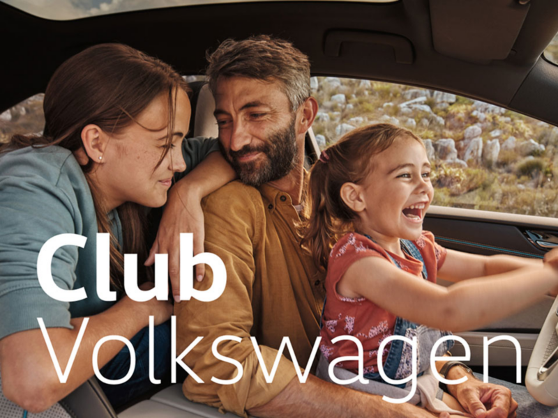 Un padre con dos niñas dentro de un Volkswagen con la frase Club Volkswagen