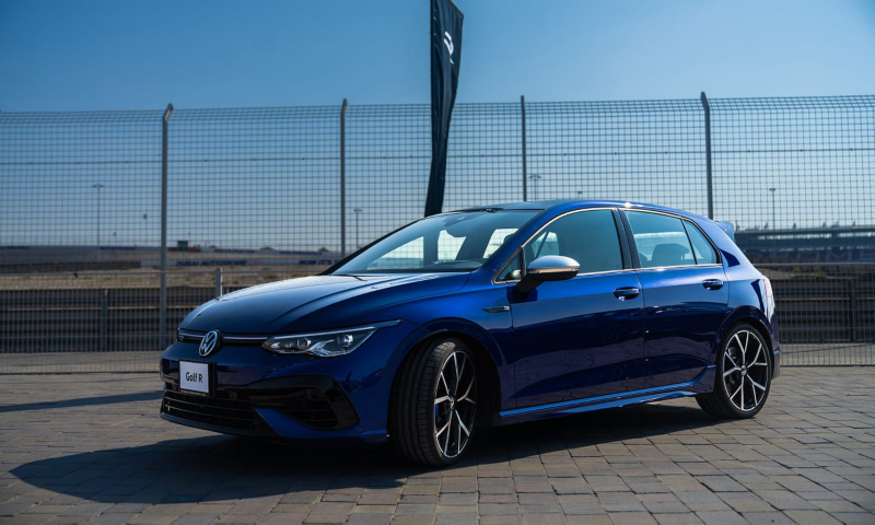 Un Volkswagen Golf R azul visto de costado estacionado delante de una verja