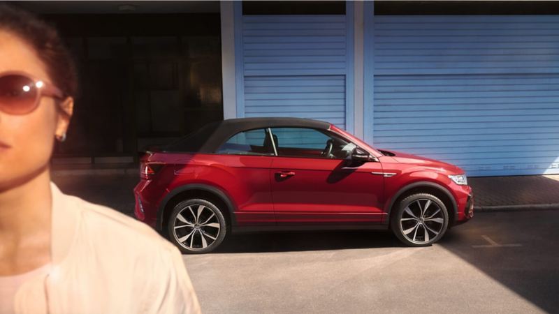Un Volkswagen T-Roc Cabrio rojo visto de costado y una chica en primer plano