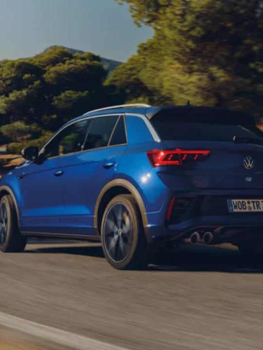 Un Volkswagen T-Roc R azul visto desde atrás en una carretera de montaña