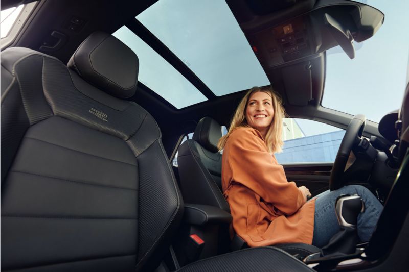 Chica de naranja sentada al volante de un Volkswagen T-Roc