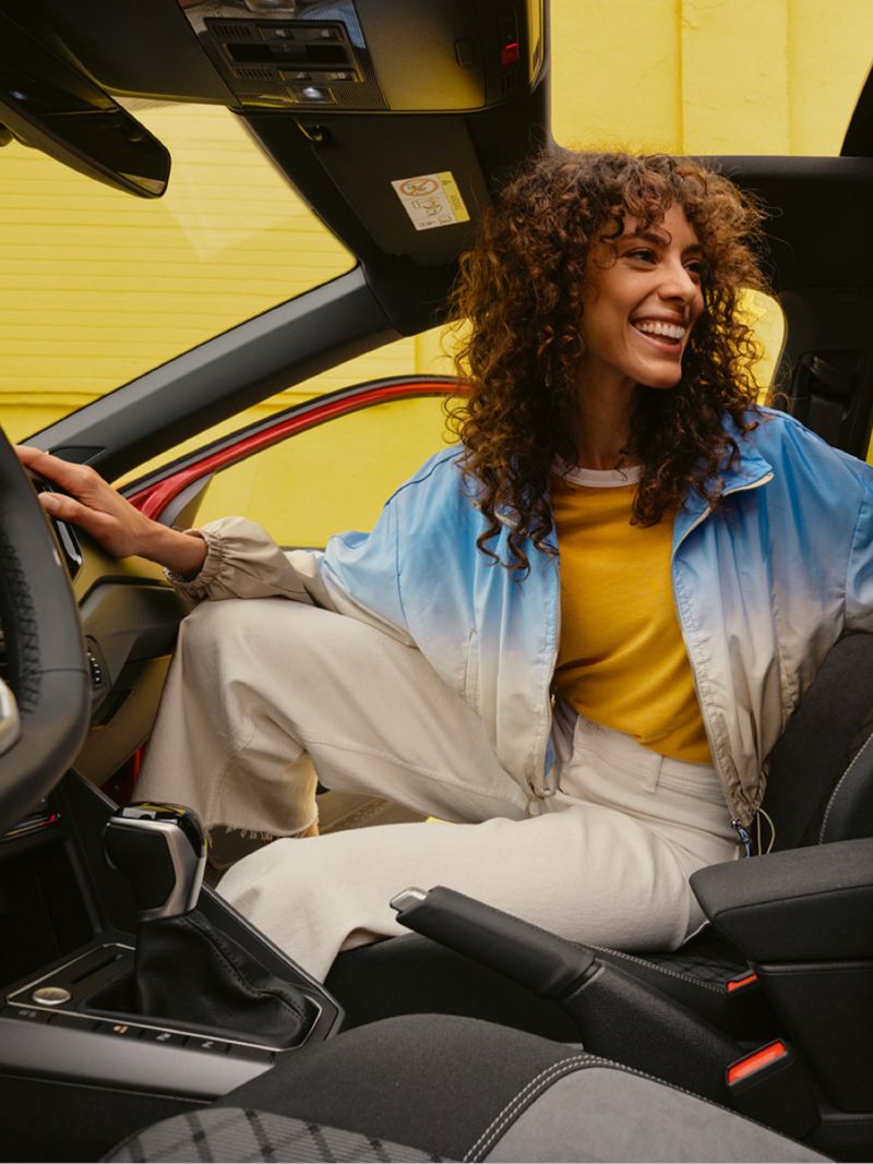 Una chica sonriendo sentada dentro de un Volkswagen Taigo