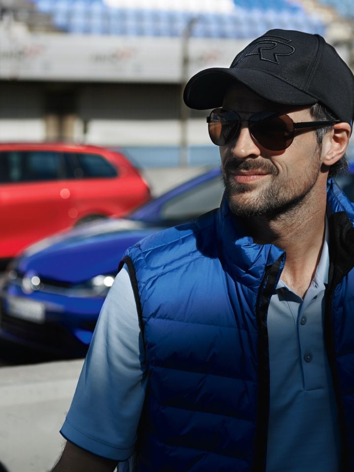 Chico con gorra y gafas de sol delante de unos modelos Volkswagen